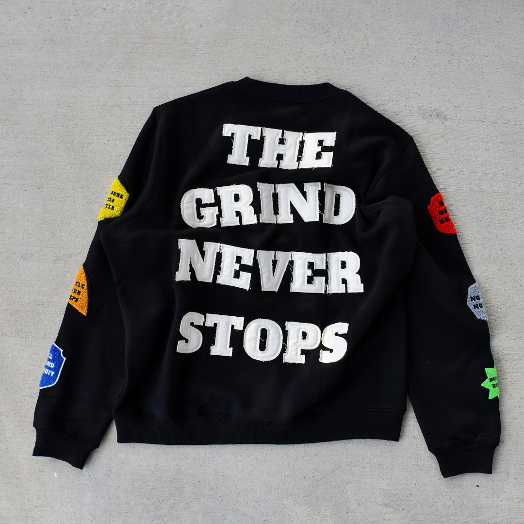 Black sweatshirt with 'The Grind Never Stops' text on a gray background