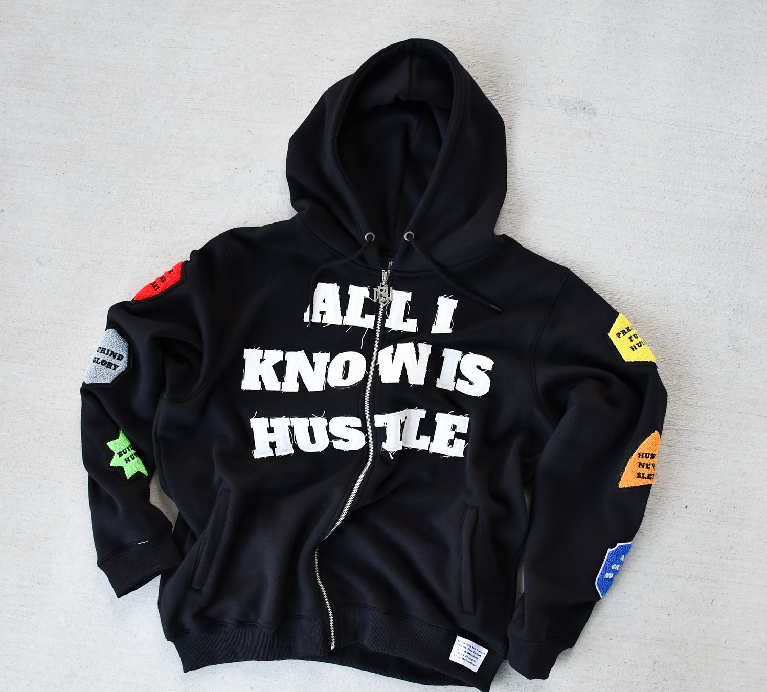 Black hoodie with 'All I Know is Hustle' text on a gray background