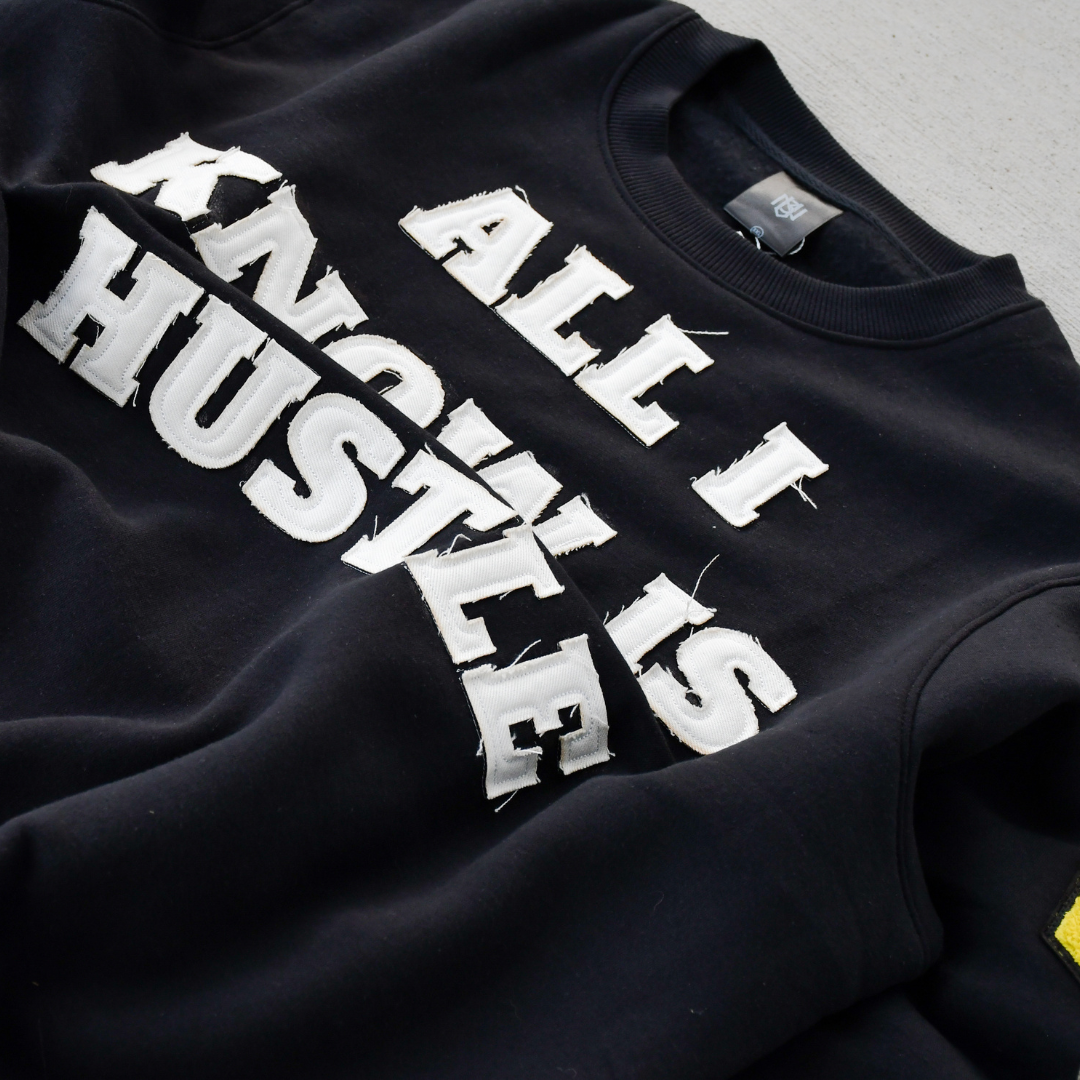Black sweatshirt with 'All I Hustle Is' text on a gray background