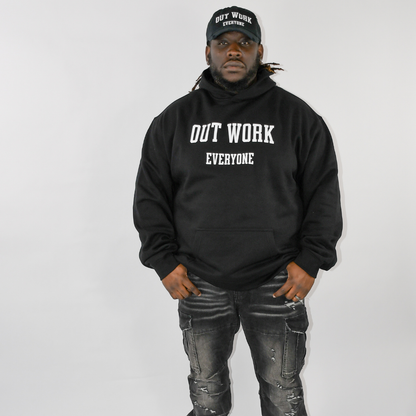 Person wearing a black hoodie with 'OUT WORK EVERYONE' text, standing against a plain background