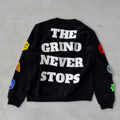 Black sweatshirt with 'The Grind Never Stops' text on a gray background